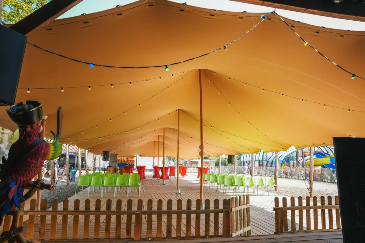 Orange stretch tent over an events area with rows of chairs and a timber deck