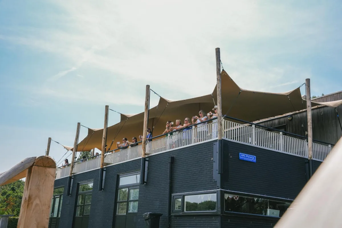 A stretch tent canopy over a first-floor terrace, with people at the rail