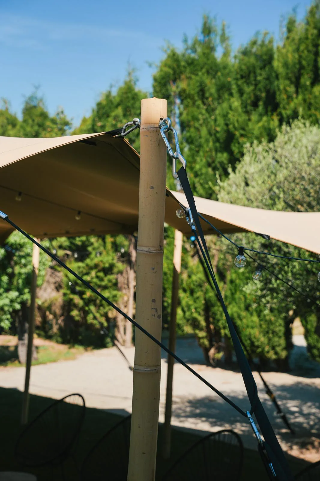 Close-up of a bamboo pole with carabiner fixings and straps holding the tent fabric